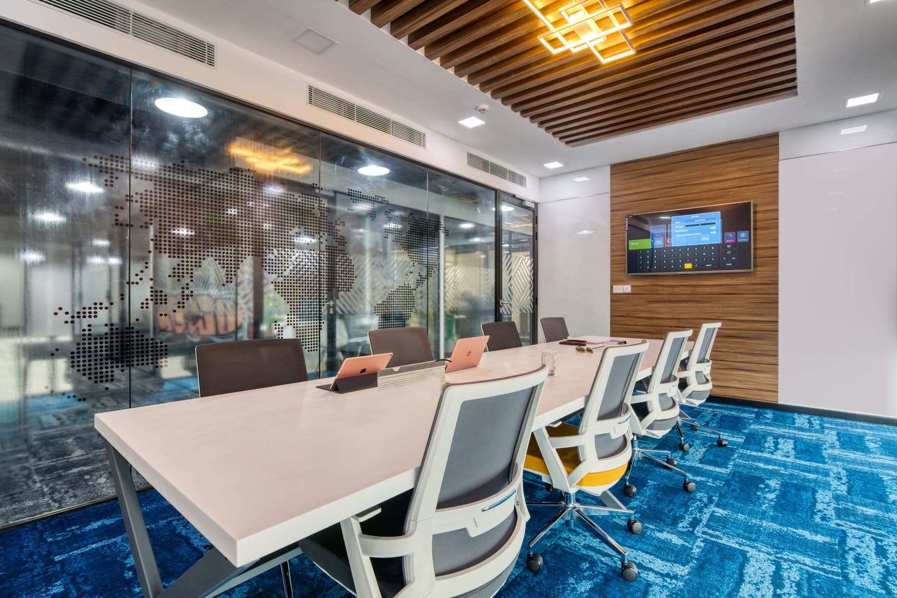 An executive boardroom with a long table, upholstered chairs and a wall screen.